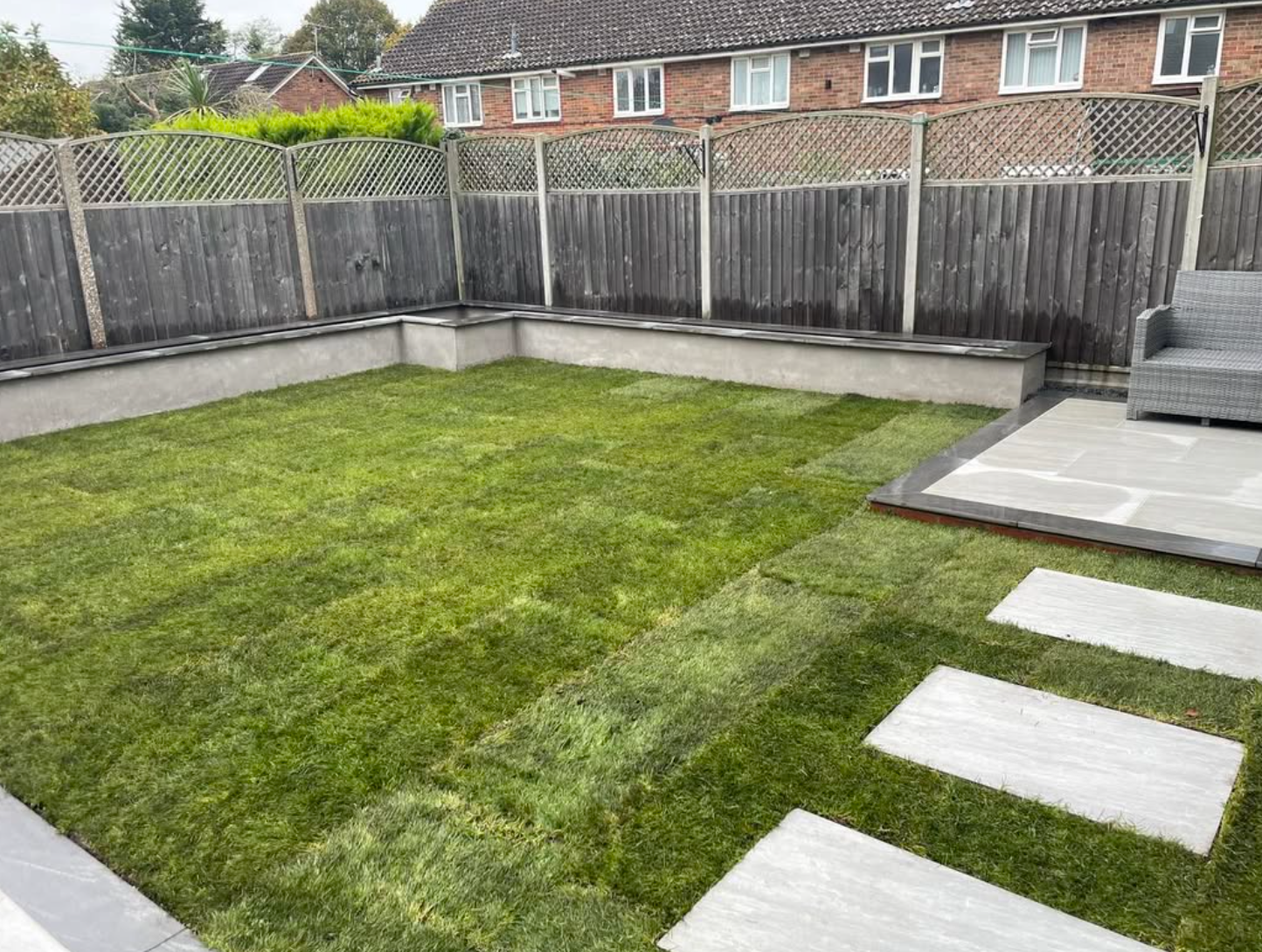 Garden lawn with stepping stones, raised edging and a paved seating area